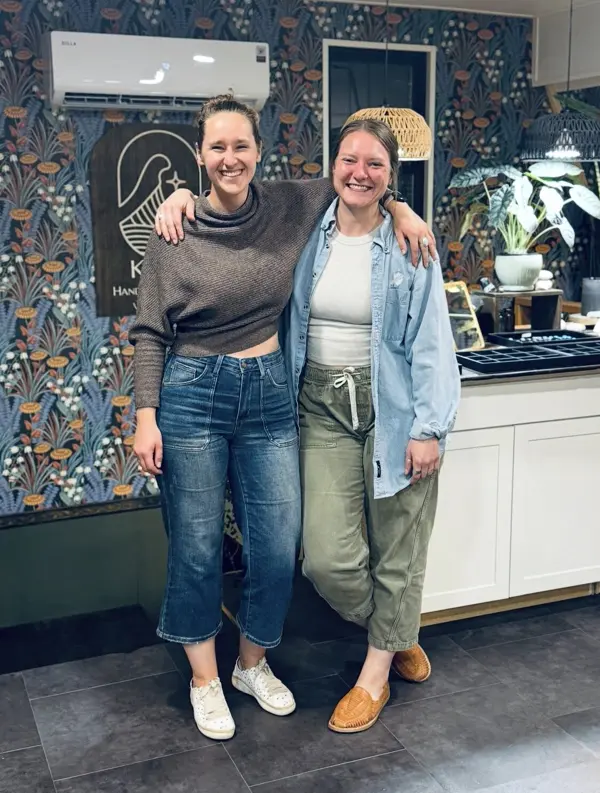 Two friends smiling by the Kukio sign